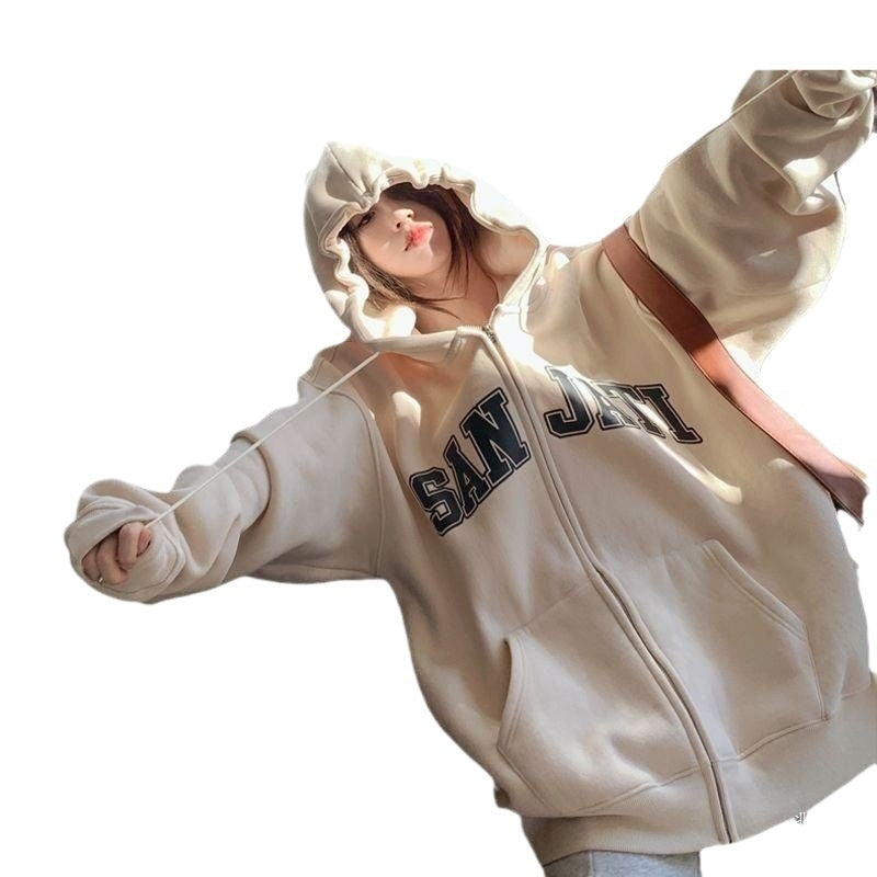 Person in beige oversized zip-up hoodie with hood up and front pockets, SAN JIN lettering.
