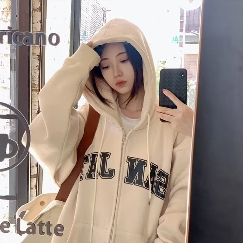 Cream oversized zip-up hoodie with hood, loose casual-style, front letters print, worn by a woman in a mirror selfie.