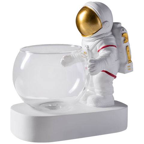 Astronaut decorative figure with gold visor holding a clear glass hydroponic flowerpot on a white base.